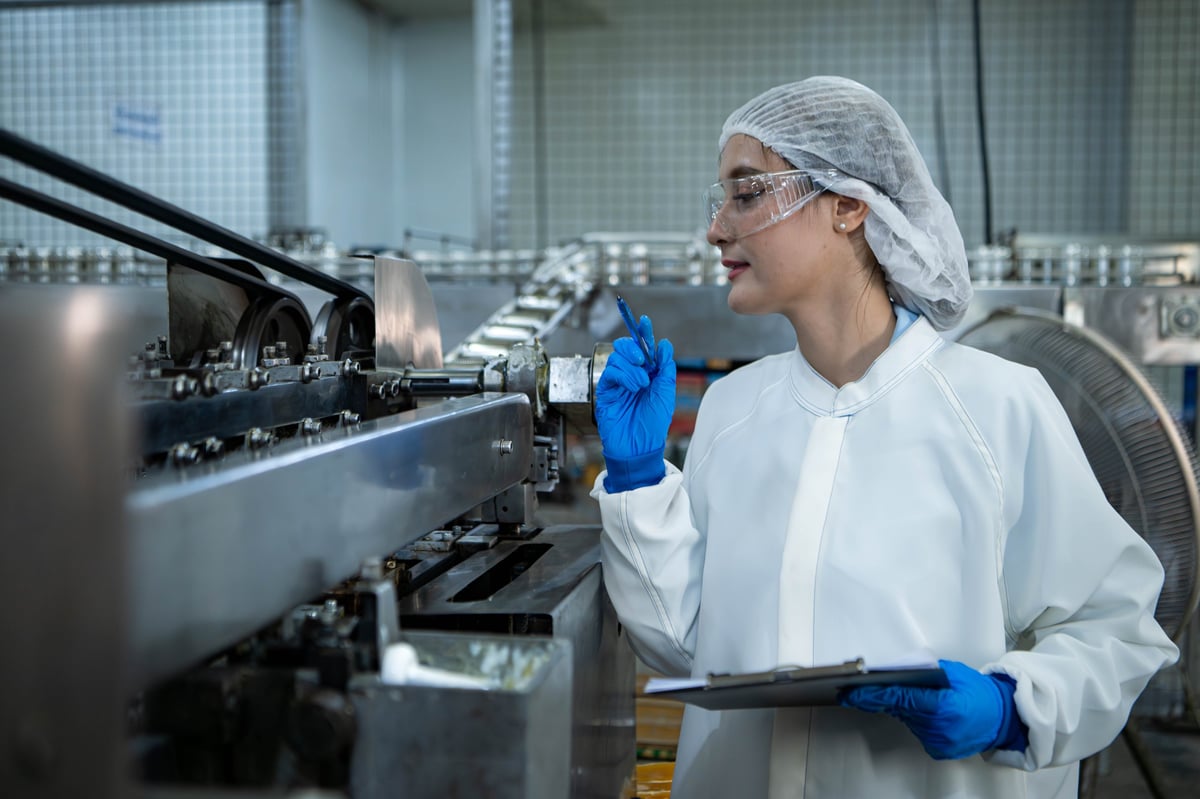 Food scientist inspecting a production line and recording quality data in a food factory